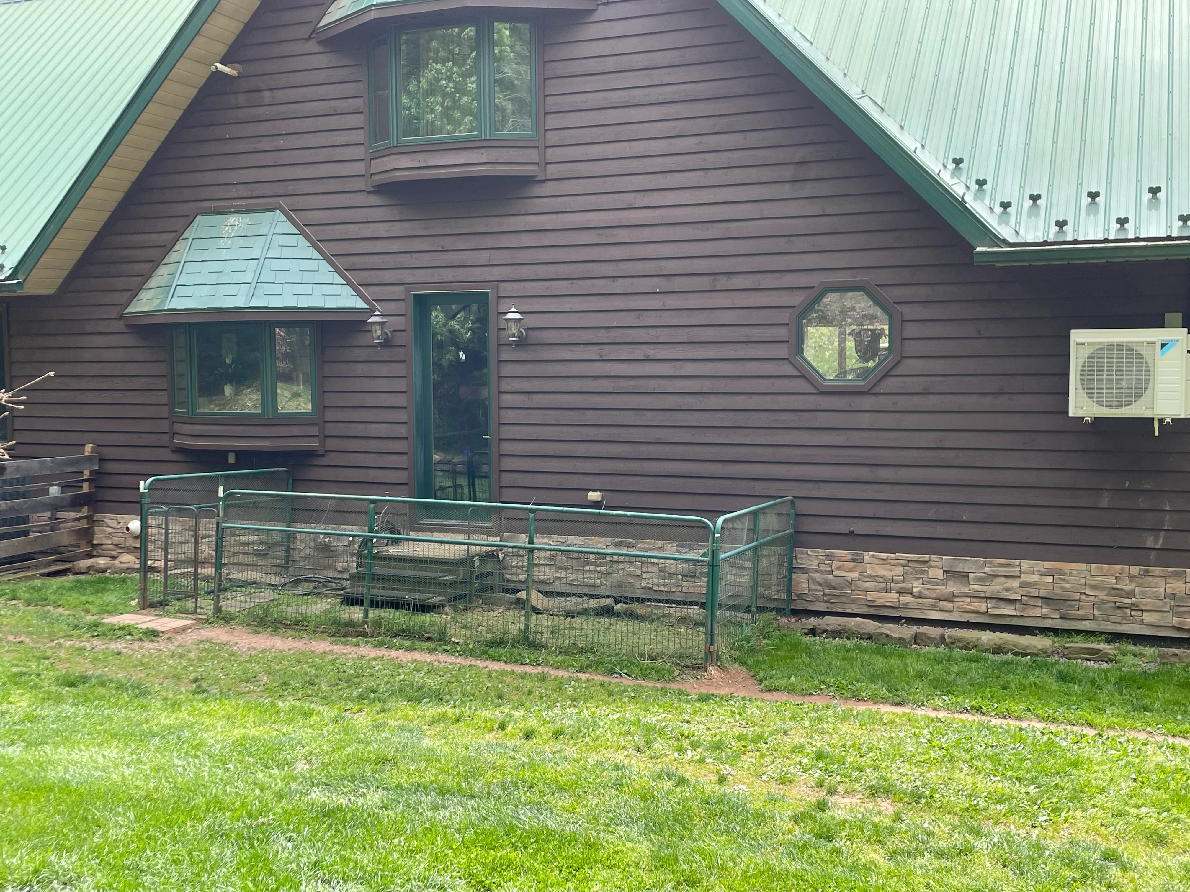 Standing seam metal roof with light green panels on residential A-frame structure, multiple roof planes